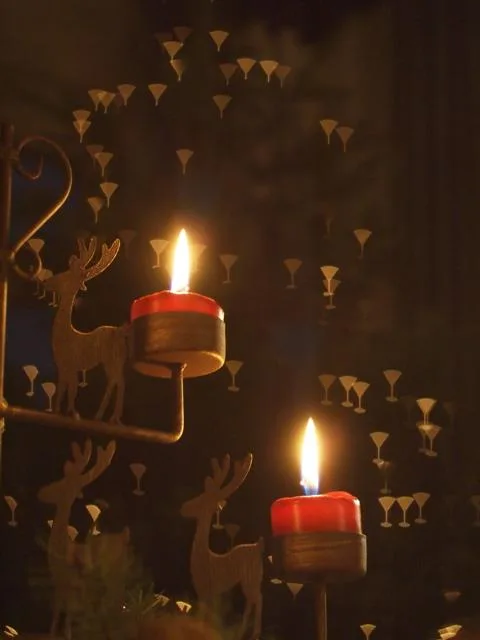 bougies Deux bougies rouges brûlent à côté d'une décoration de renne en bois