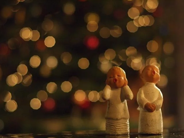anges Deux petites figurines d'ange devant des lumières de Noël floues