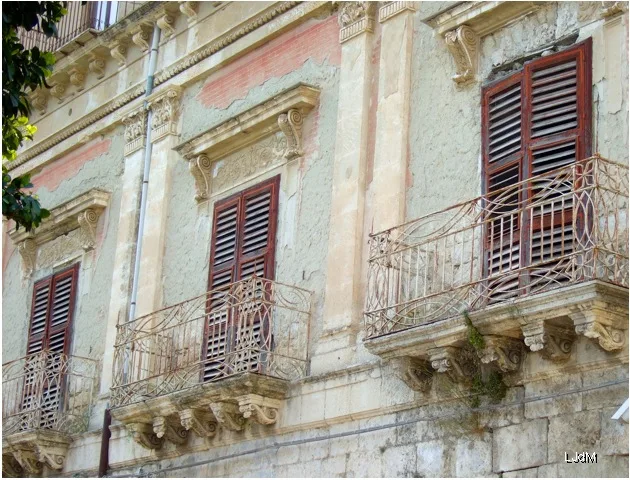 Balcon baroque patiné sur un immeuble à Favara