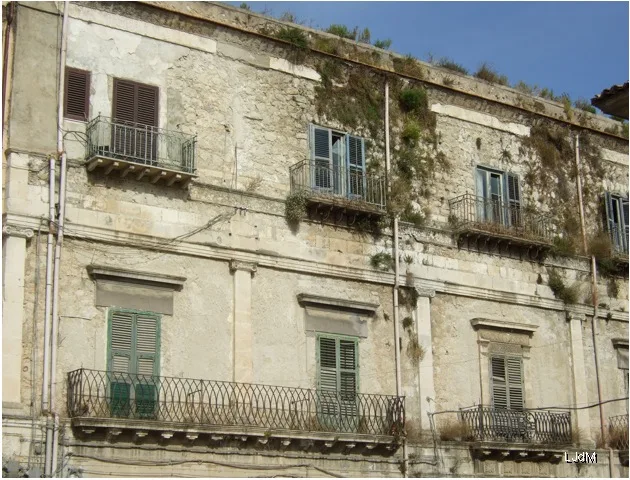 Façade historique patinée avec balcons en fer à Favara