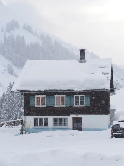 Chalet en bois sombre recouvert de neige épaisse