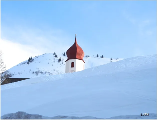 Clocher rouge de l'église s'élevant au-dessus d'une colline enneigée