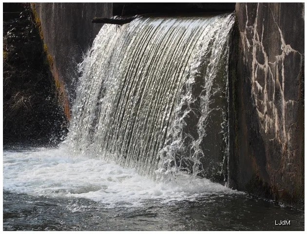 L'eau tombe en cascade sur une porte d'écluse du canal