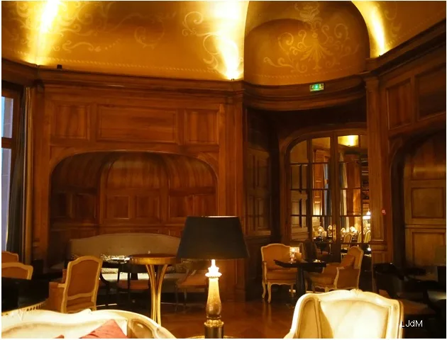 Fumoir lambrissé avec fauteuils et lampe de table allumée