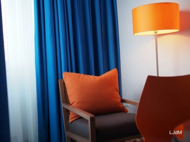 Fauteuil et lampadaire orange contre rideaux bleus