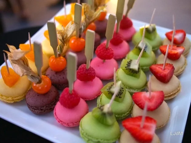 Macarons colorés et canapés aux fruits sur un plateau de service