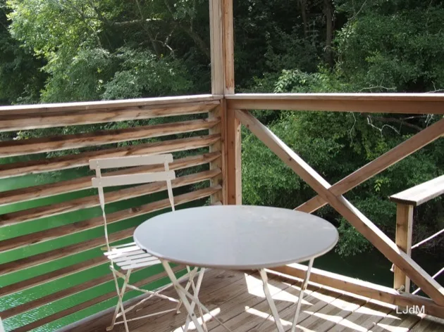 Table et chaises sur un balcon en bois donnant sur verdure
