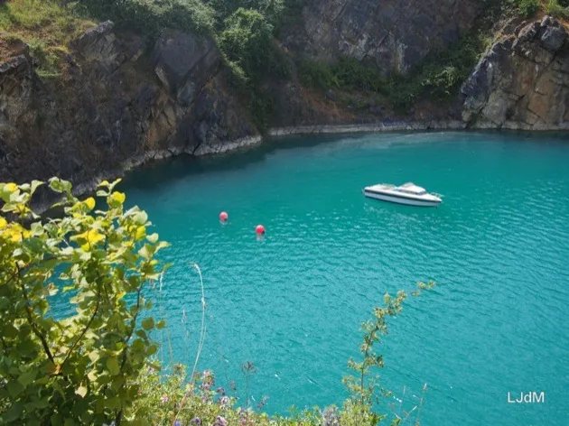 Lac de carrière turquoise avec un petit bateau en contrebas
