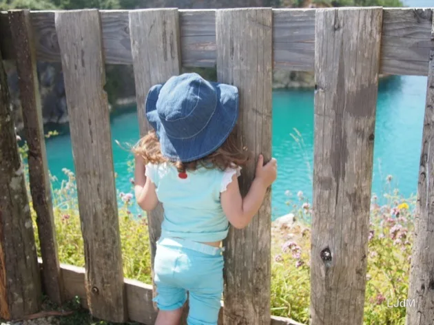 Famille vue de derrière regardant à travers une clôture au-dessus d'une carrière turquoise