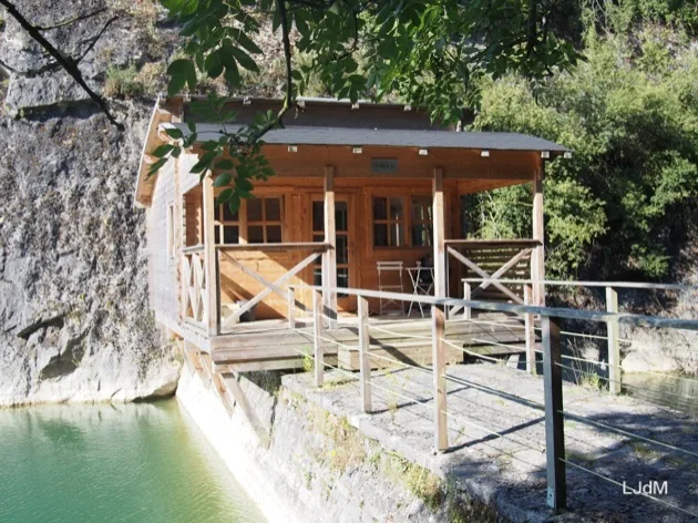 Cabane en bois au bord de l'eau construite contre un mur de carrière rocheux