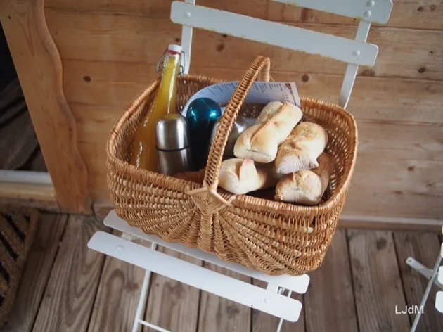 Panier petit-déjeuner avec pain et boissons sur la terrasse d'une cabane