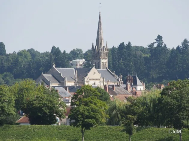 Flèche d'église s'élevant au-dessus d'un village au bord du canal
