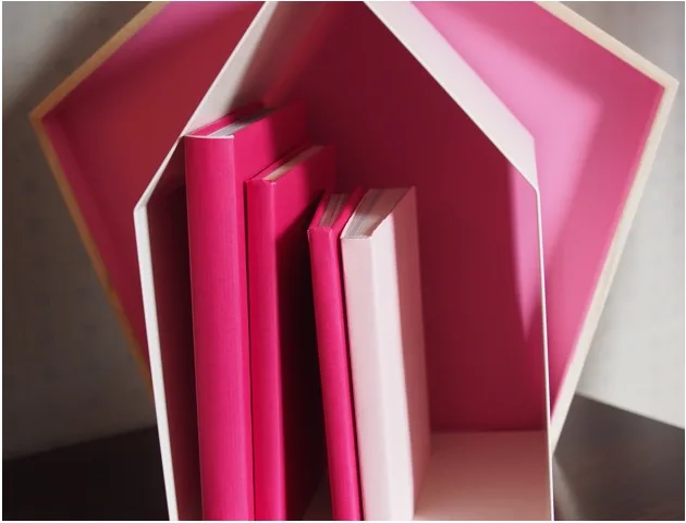 Carnets roses exposés sur une étagère en forme de maison