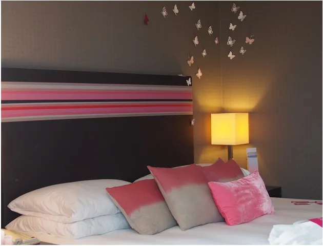 Coussins roses et décorations papillons dans une chambre d'hôtel