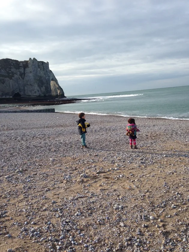 Famille marchant sur la plage de galets d’Étretat