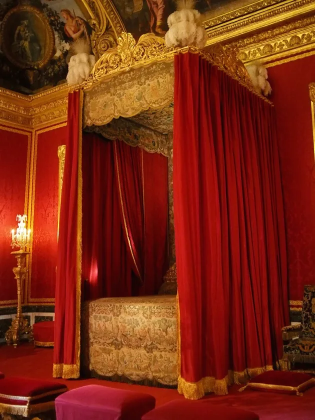 Lit royal sous des rideaux de velours rouge