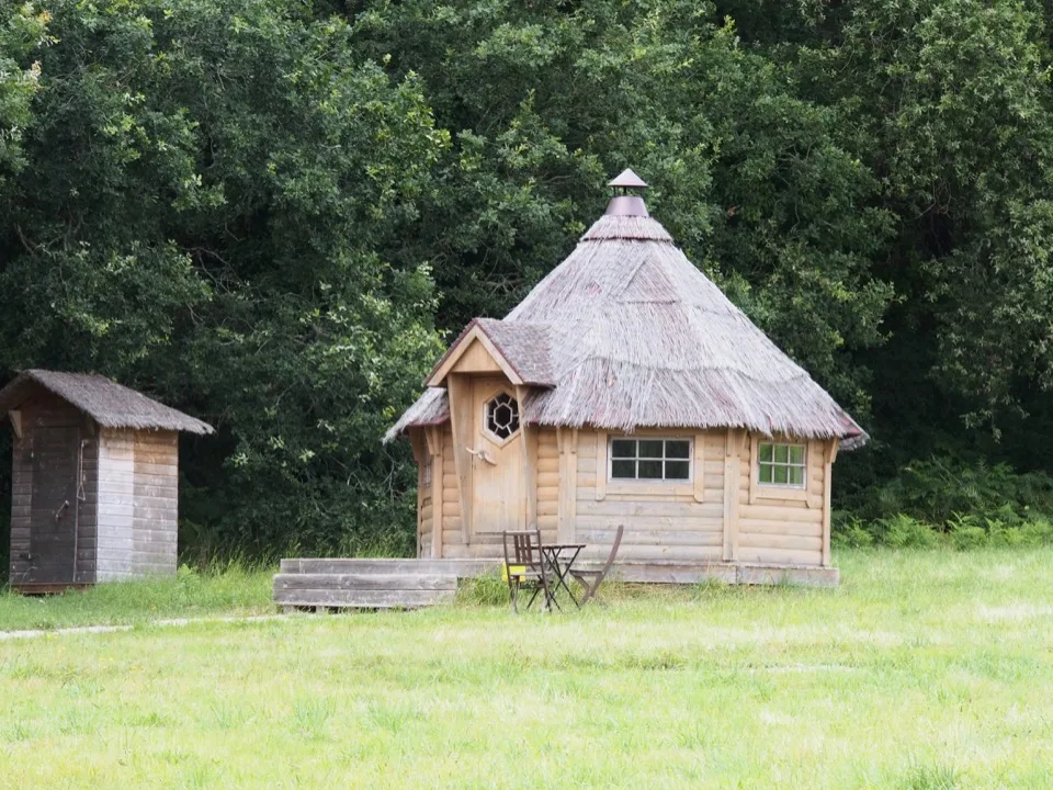 Petite cabane ronde en bois dans une clairière