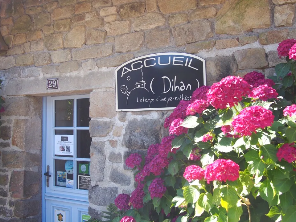 Bâtiment d'accueil en pierre à Dihan avec hortensias roses