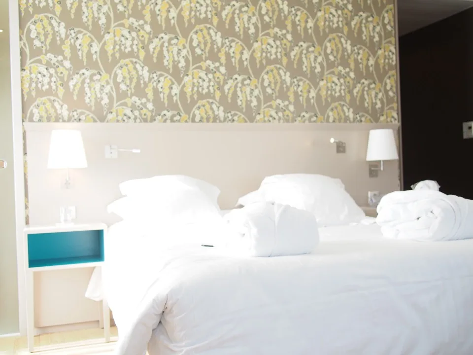 Chambre d'hôtel lumineuse avec papier peint à motifs