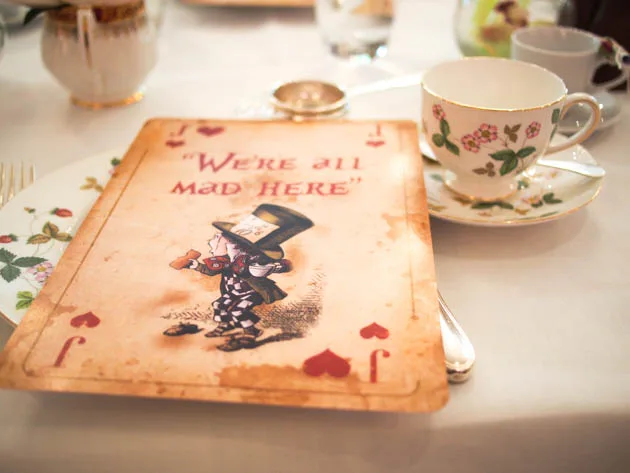 Menu Alice au Pays des Merveilles à côté d’une tasse de thé fleurie