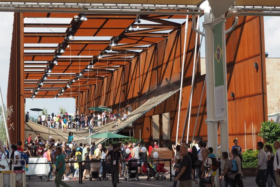 Foules se déplaçant dans un pavillon au toit orange de l’Expo Milano