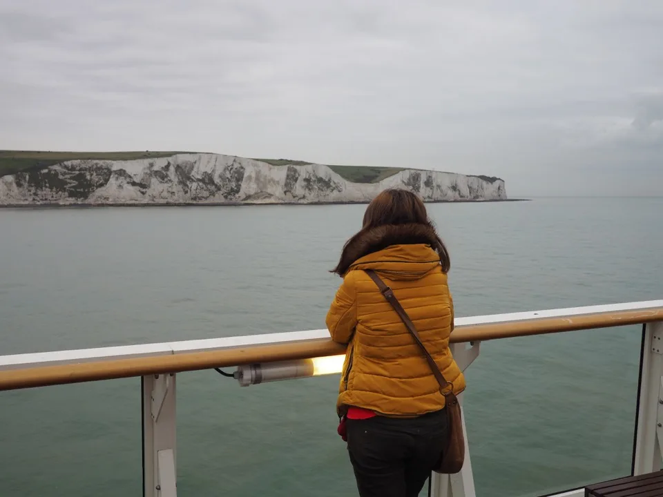 Voyageuse de dos face aux falaises blanches depuis un ferry