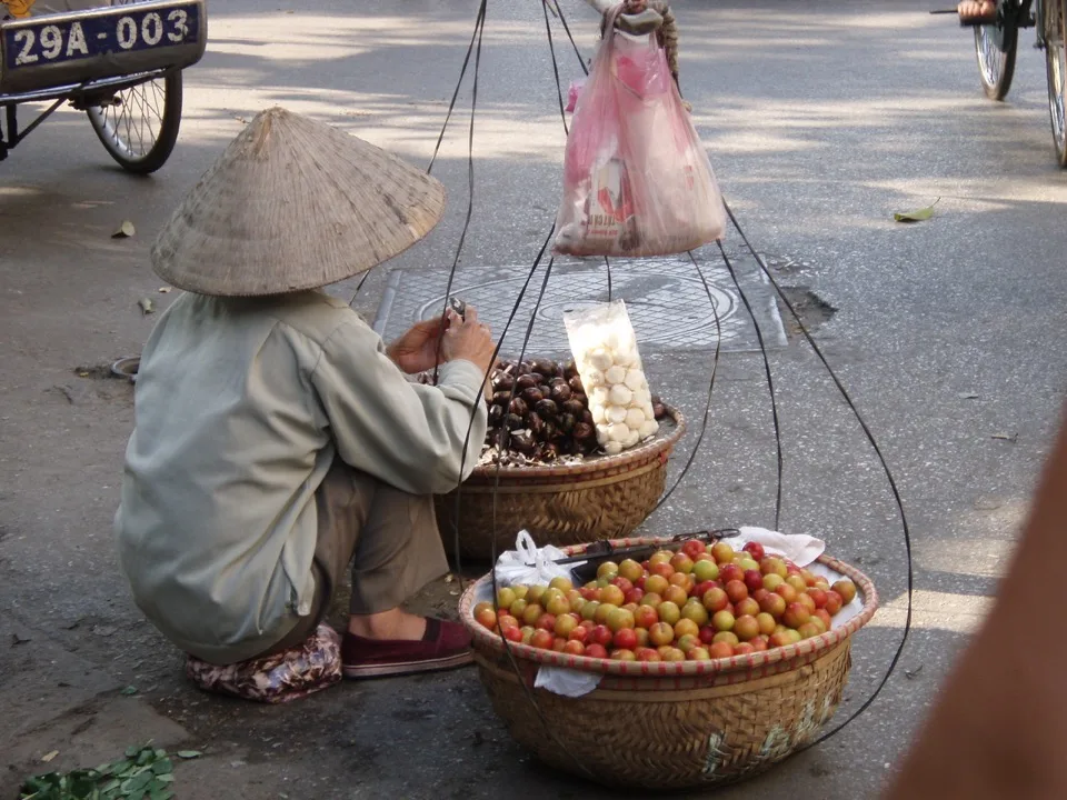 Vendeur ambulant avec des paniers de fruits au Vietnam