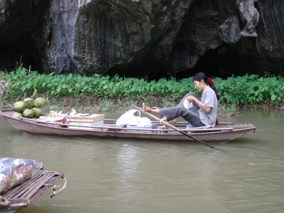 Vendeur ramant un bateau étroit chargé de noix de coco
