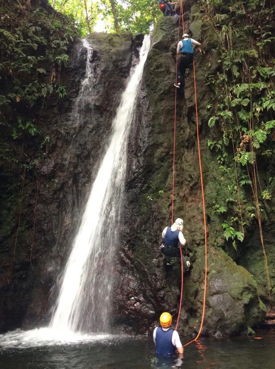 Famille en rappel à côté d'une grande cascade