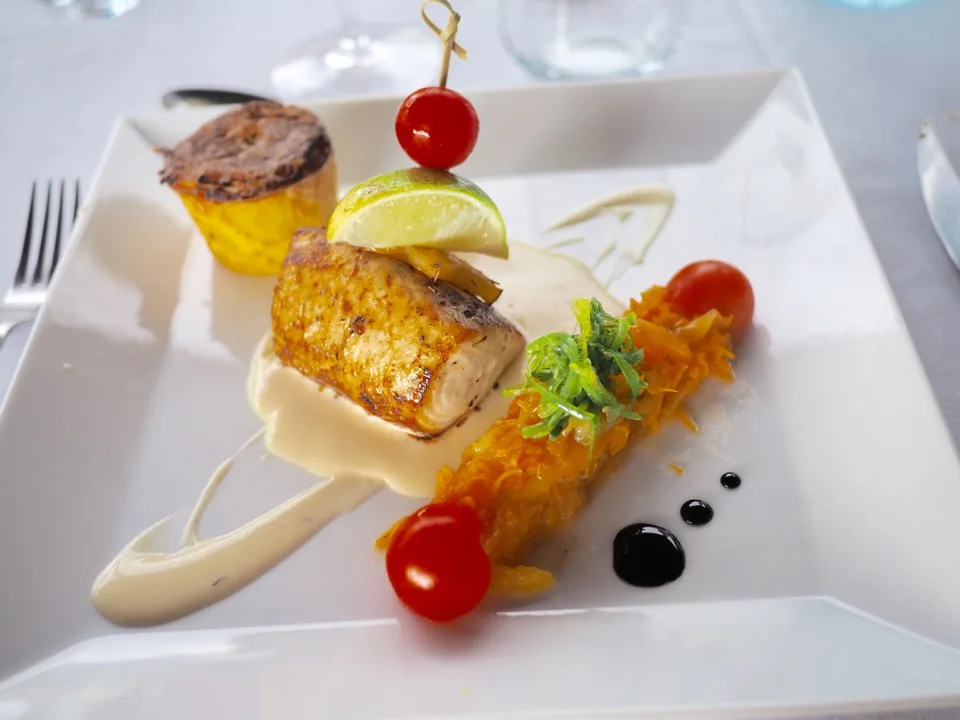 Poisson grillé avec légumes et sauce sur une assiette blanche