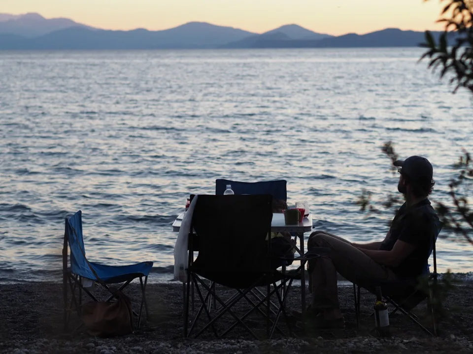 Voyageurs se détendant au bord d’un lac dans un camping pour camping-cars