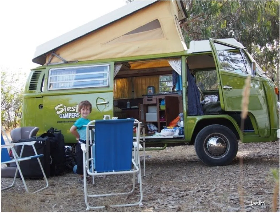 Camping-car Volkswagen vert dans un camping boisé