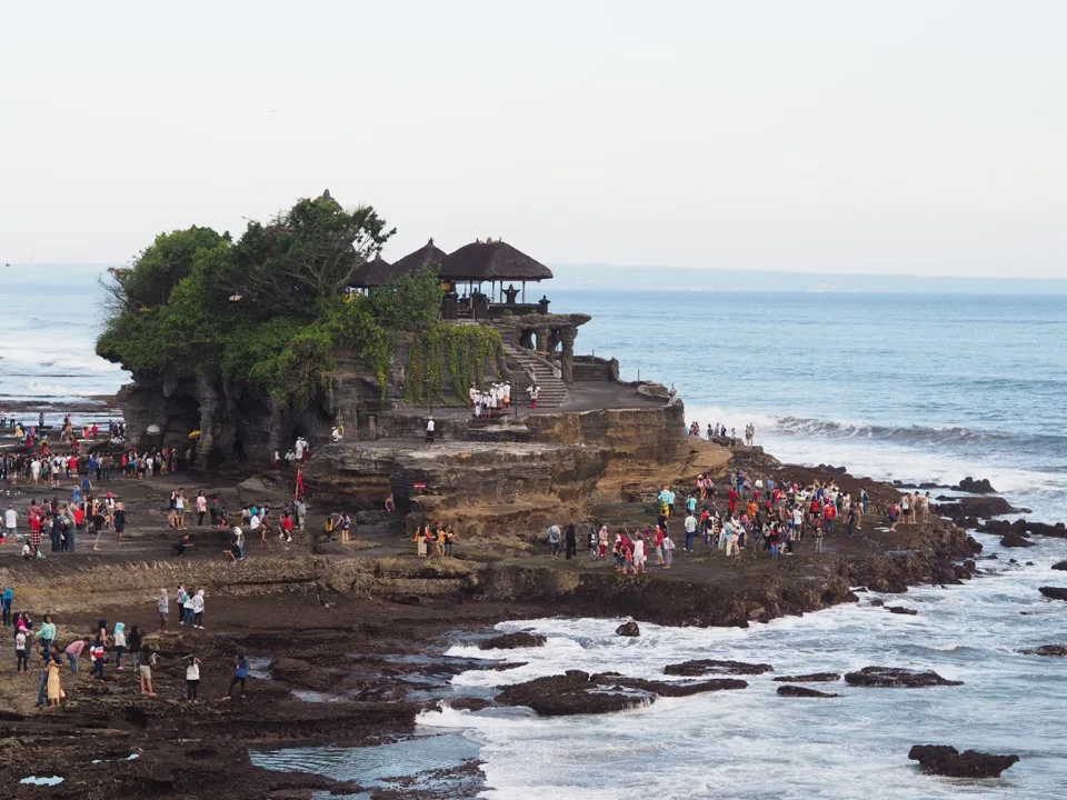 Visiteurs traversant les rochers sous le temple de Tanah Lot