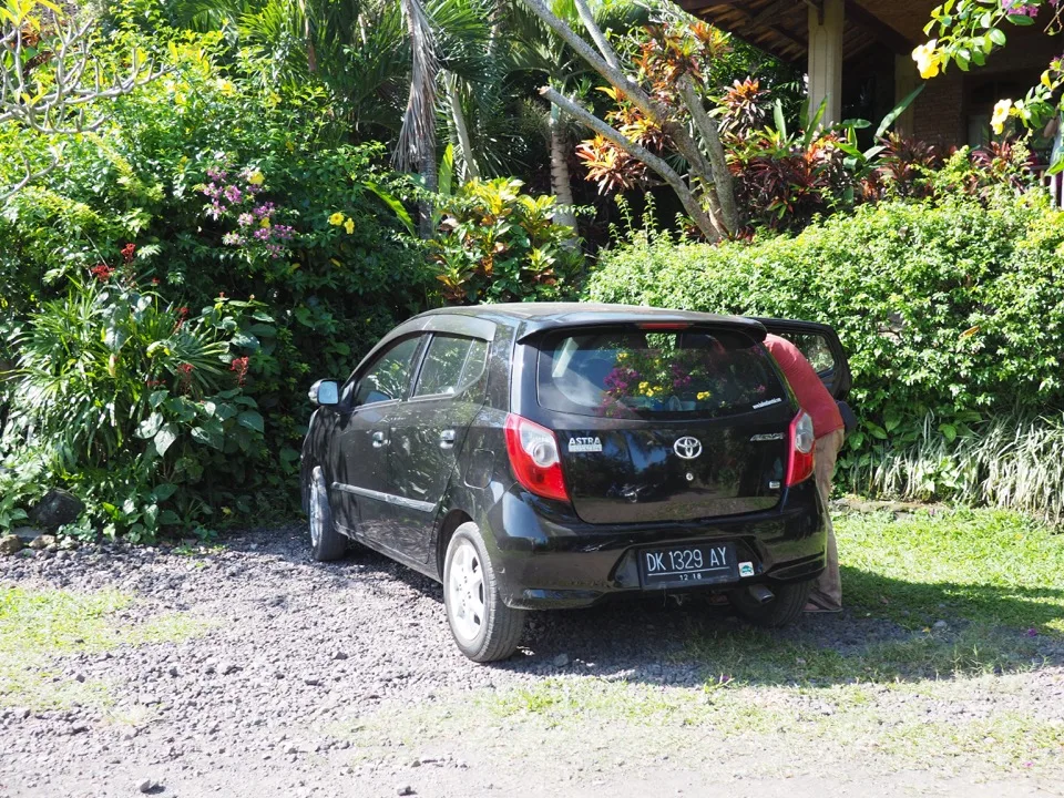 Voiture de location noire garée dans un jardin à Bali