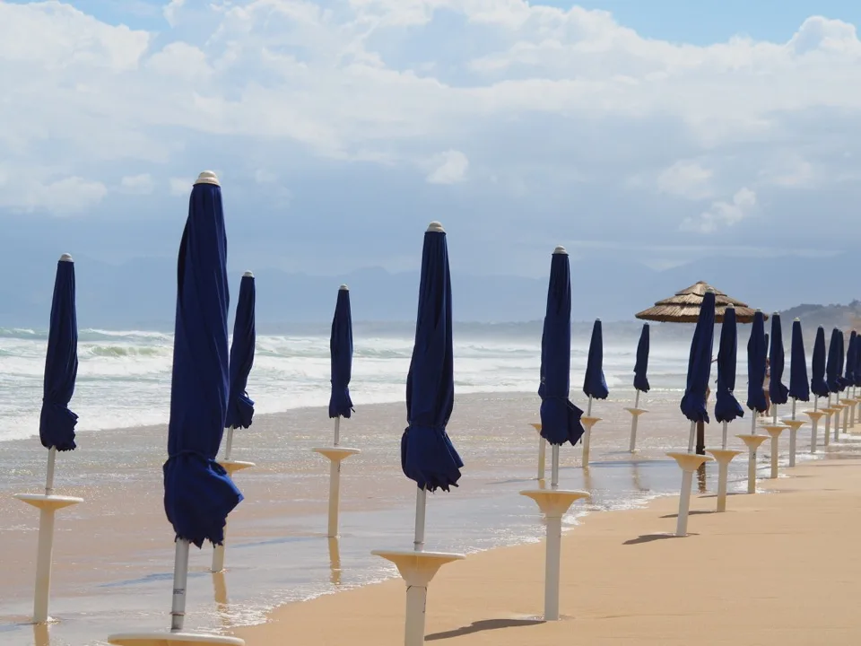 Parasols fermés alignés sur une plage de Castellammare del Golfo
