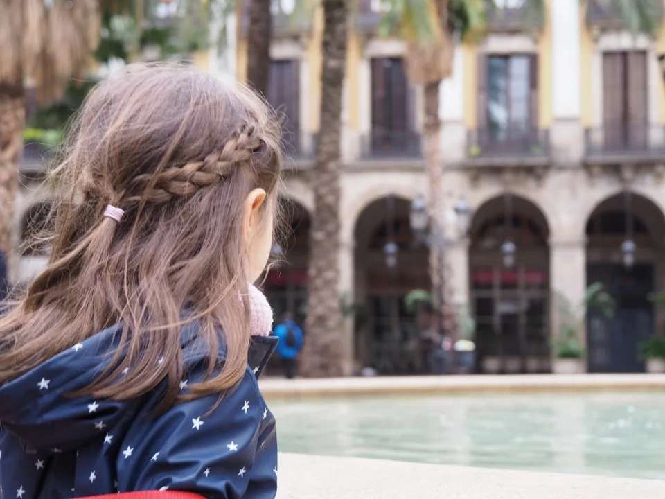 Un membre de la famille vu de derrière devant une fontaine dans une cour de Barcelone