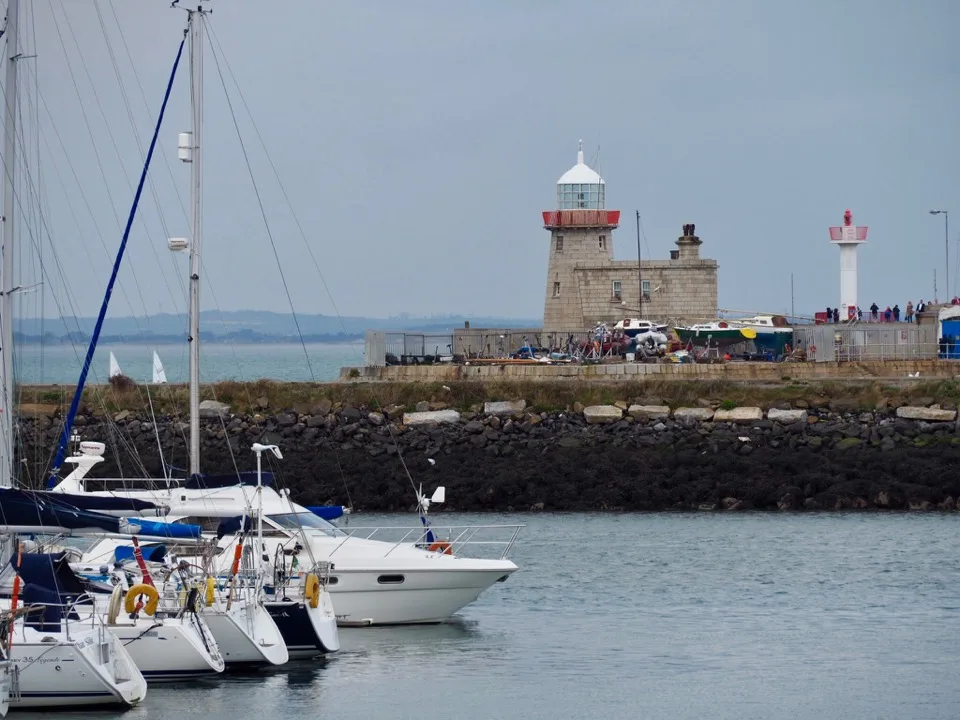 Segelboote vor einem rot-weißen Leuchtturm in Nordirland