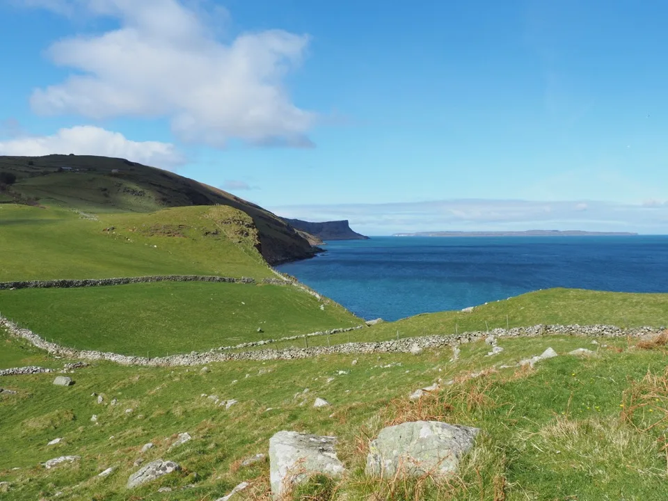 Grüne Küste Nordirlands unter blauem Himmel
