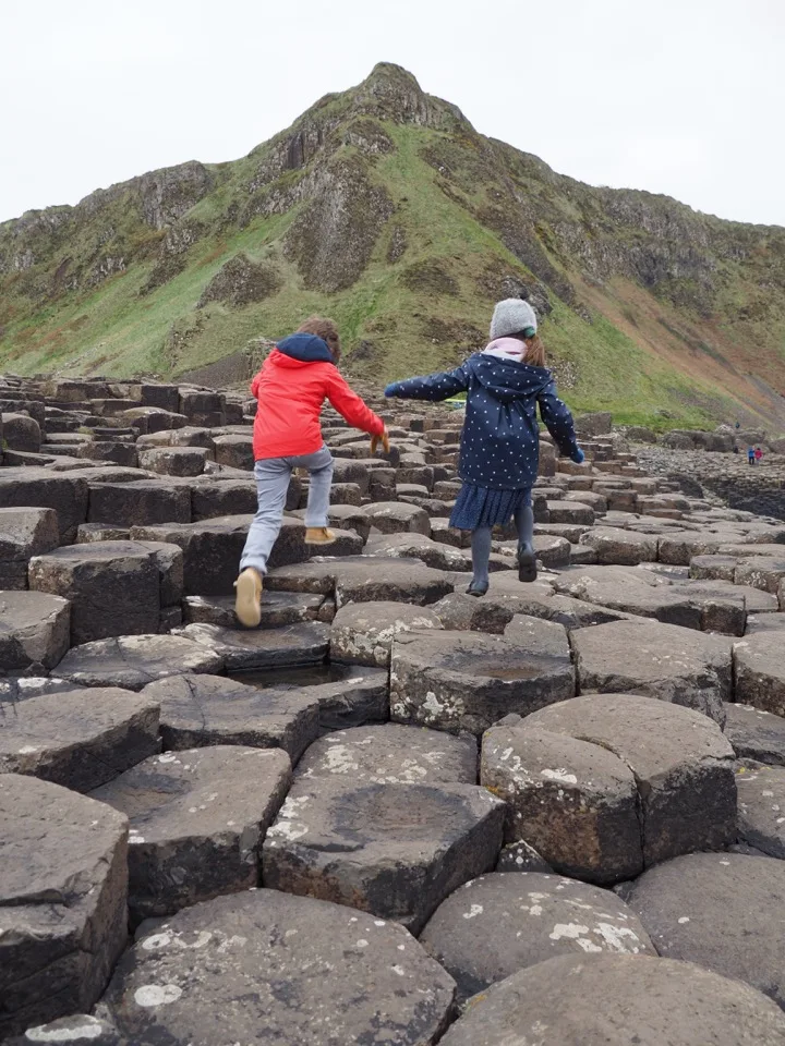 Familie von hinten auf den Säulen des Giant's Causeway