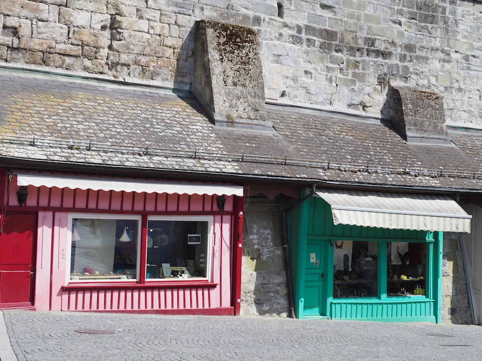 Des devantures colorées sous un vieux bâtiment en pierre