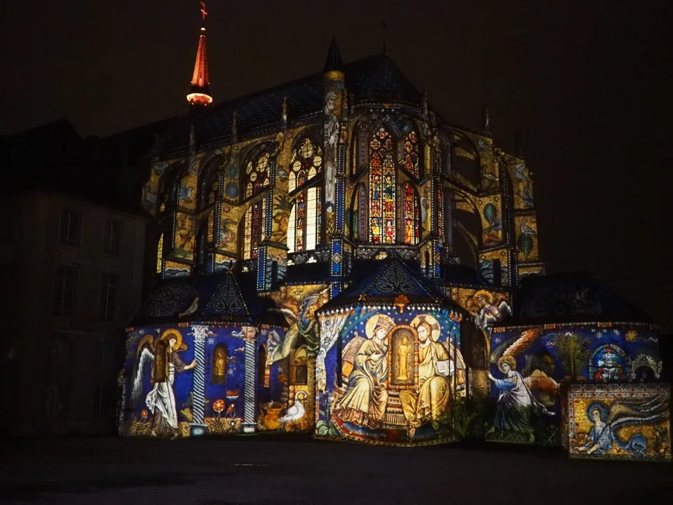 Façade de l'église éclairée la nuit par des personnages médiévaux