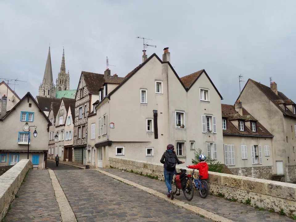 Famille avec vélos sur un pont de pierre dans la vieille ville de Chartres