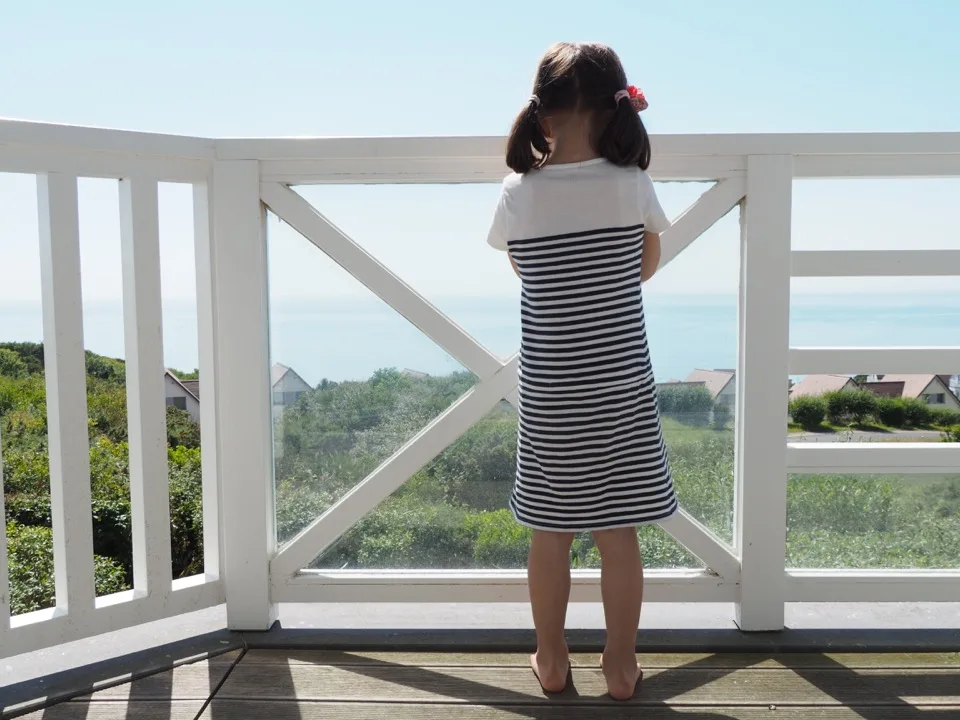 Famille de dos sur le balcon d'une maison à Équihen-Plage