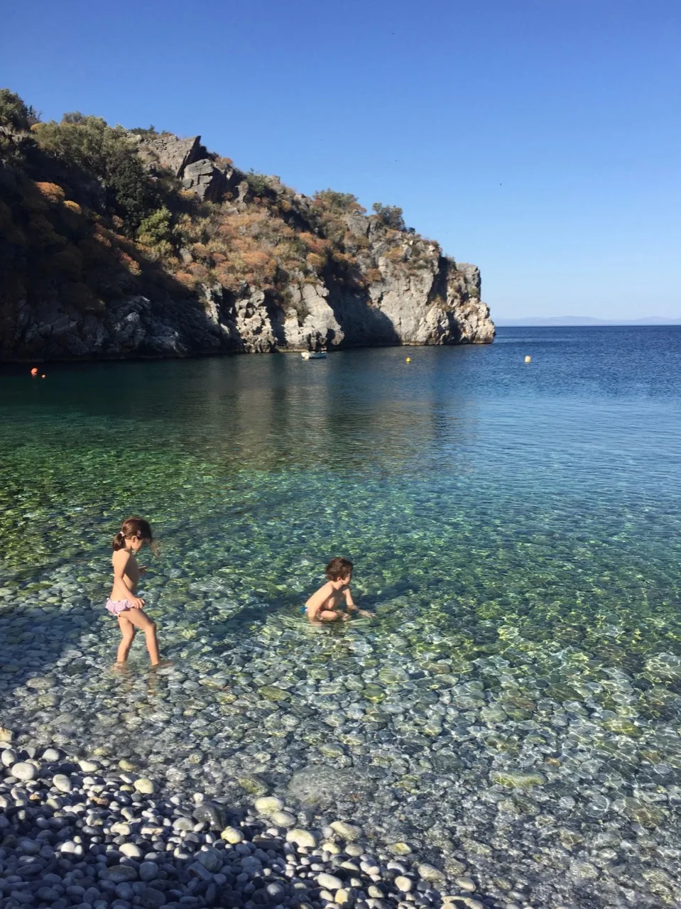 Famille de dos dans l’eau transparente d’une crique du Magne