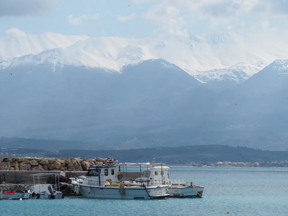 Panoramic view of the snow-capped White Mountains behind a Cretan harbour