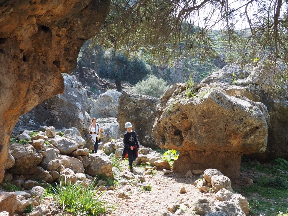 Children seen from behind walking through a rocky gorge in Crete