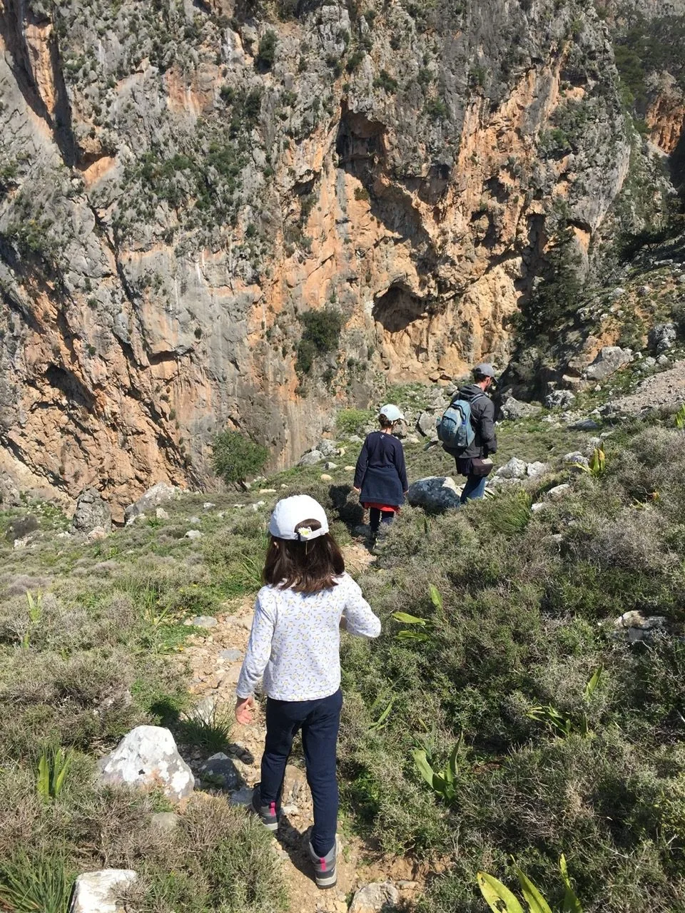 Family seen from behind on a stony trail in Crete