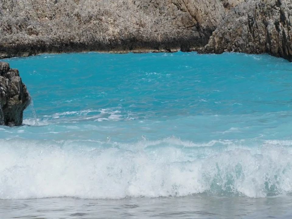 Turquoise wave on a beach between Cretan cliffs