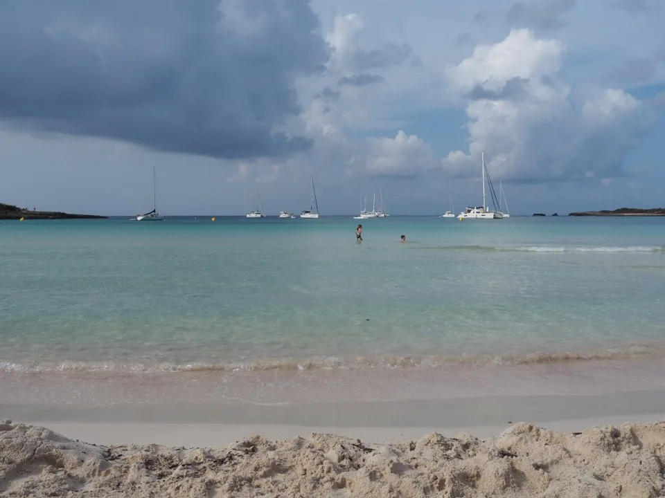 Flaches türkisfarbenes Wasser und Segelboote vor dem Strand Son Saura