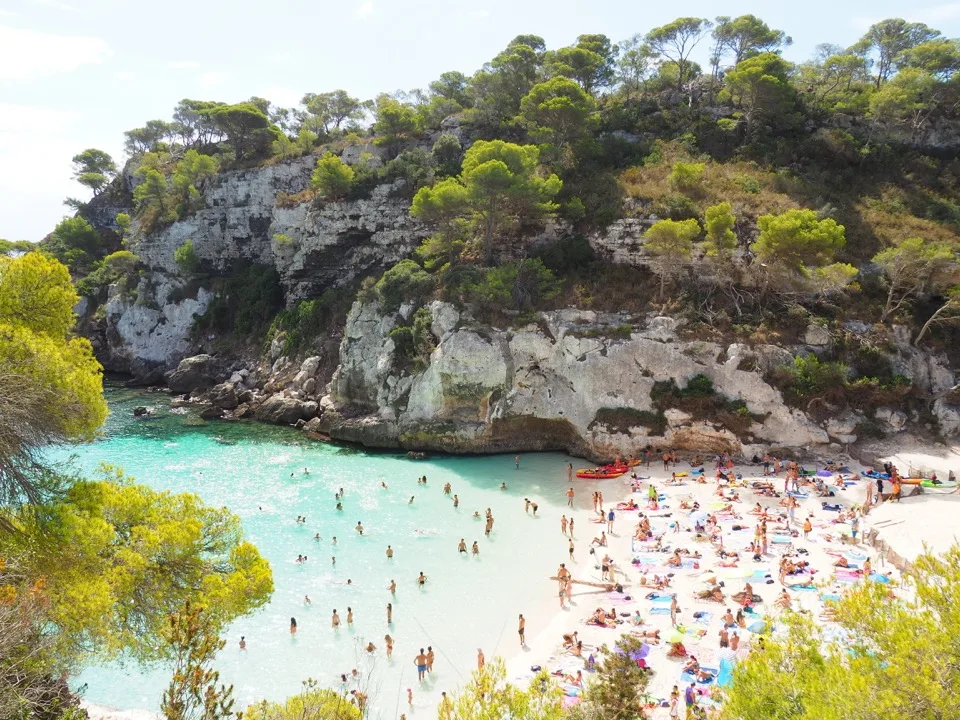 Strand der Cala Macarelleta unter bewaldeten Klippen